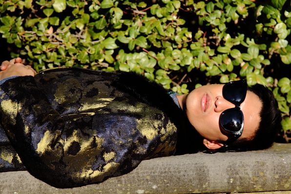 Bryanboy lying down on a bench in Antonio Marras coat at the Boboli Gardens, Florence