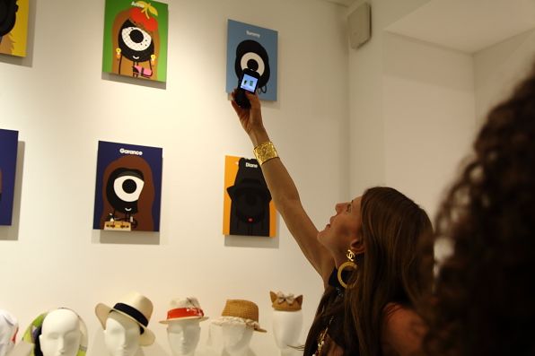 Anna dello Russo taking a photo of her portrait by Darcel at Colette, Paris