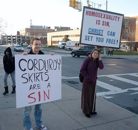 Chris Pesto holding a 'Corduroy Skirts are Sin' sign.